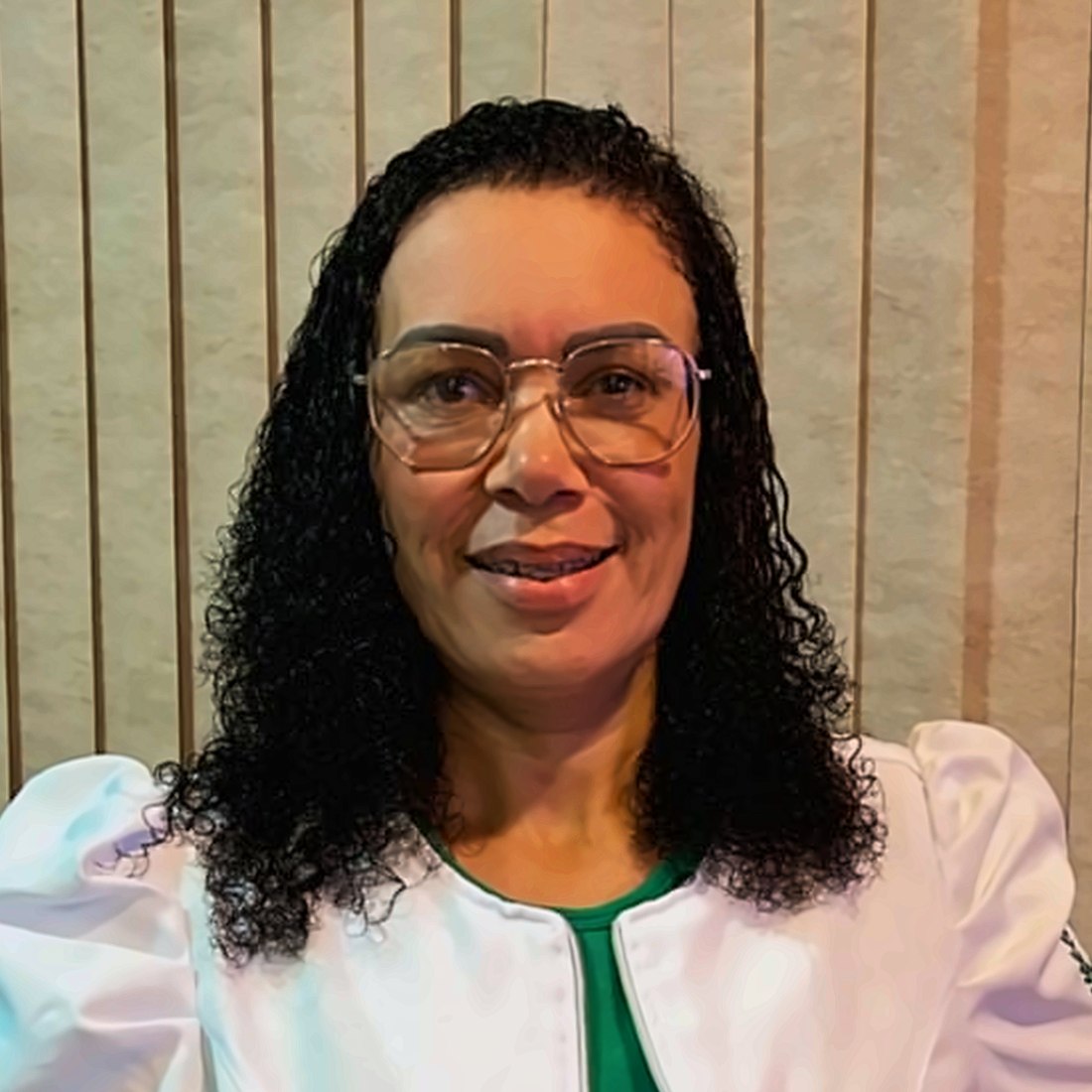 Retrato de Patrícia Mota, psicóloga, de jaleco branco, sorrindo.